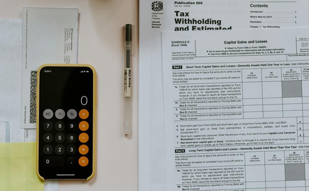 black Android smartphone near ballpoint pen, tax withholding certificate on top of white folder